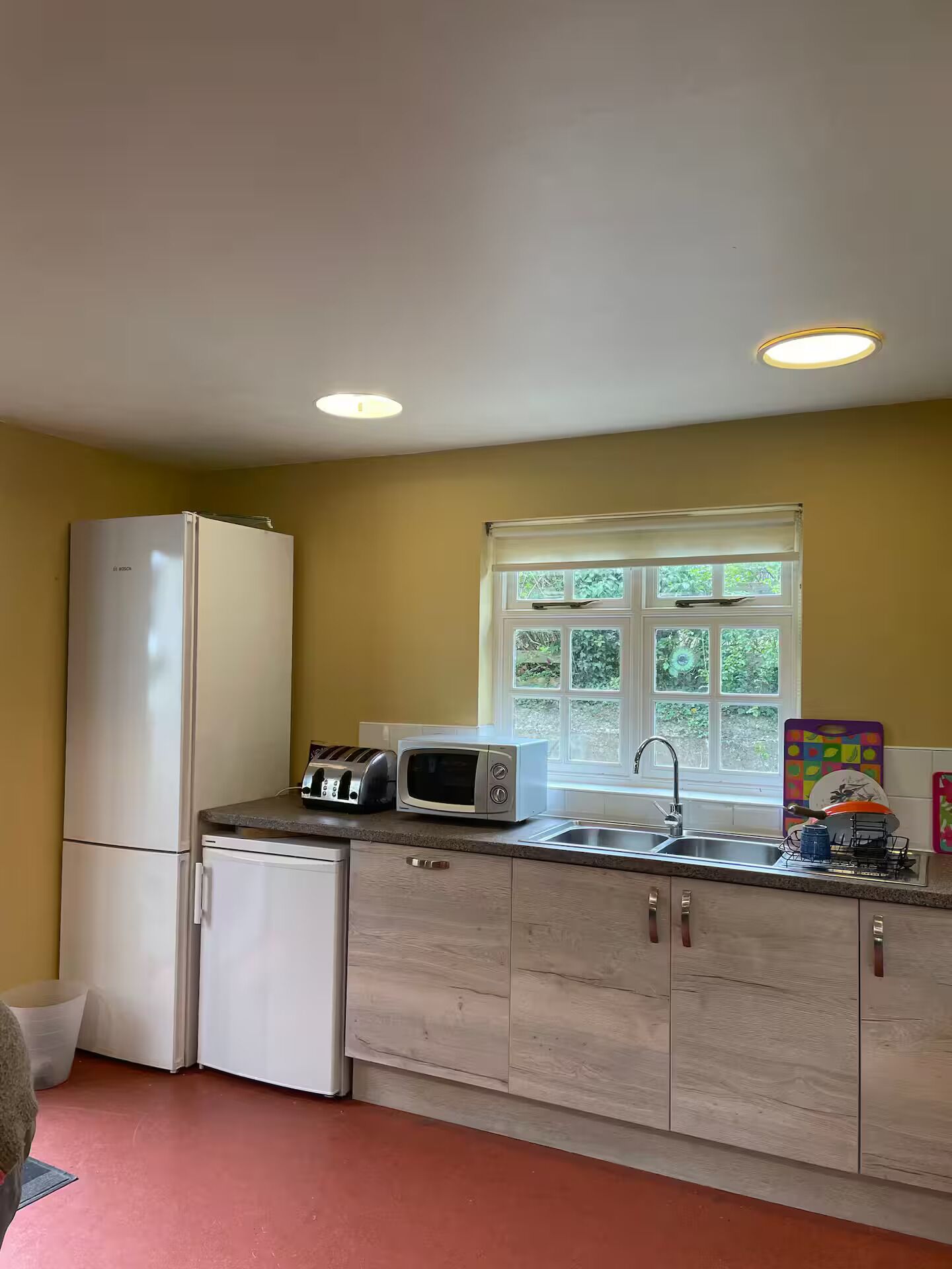 A compact kitchen with a refrigerator, microwave, toaster, and sink.