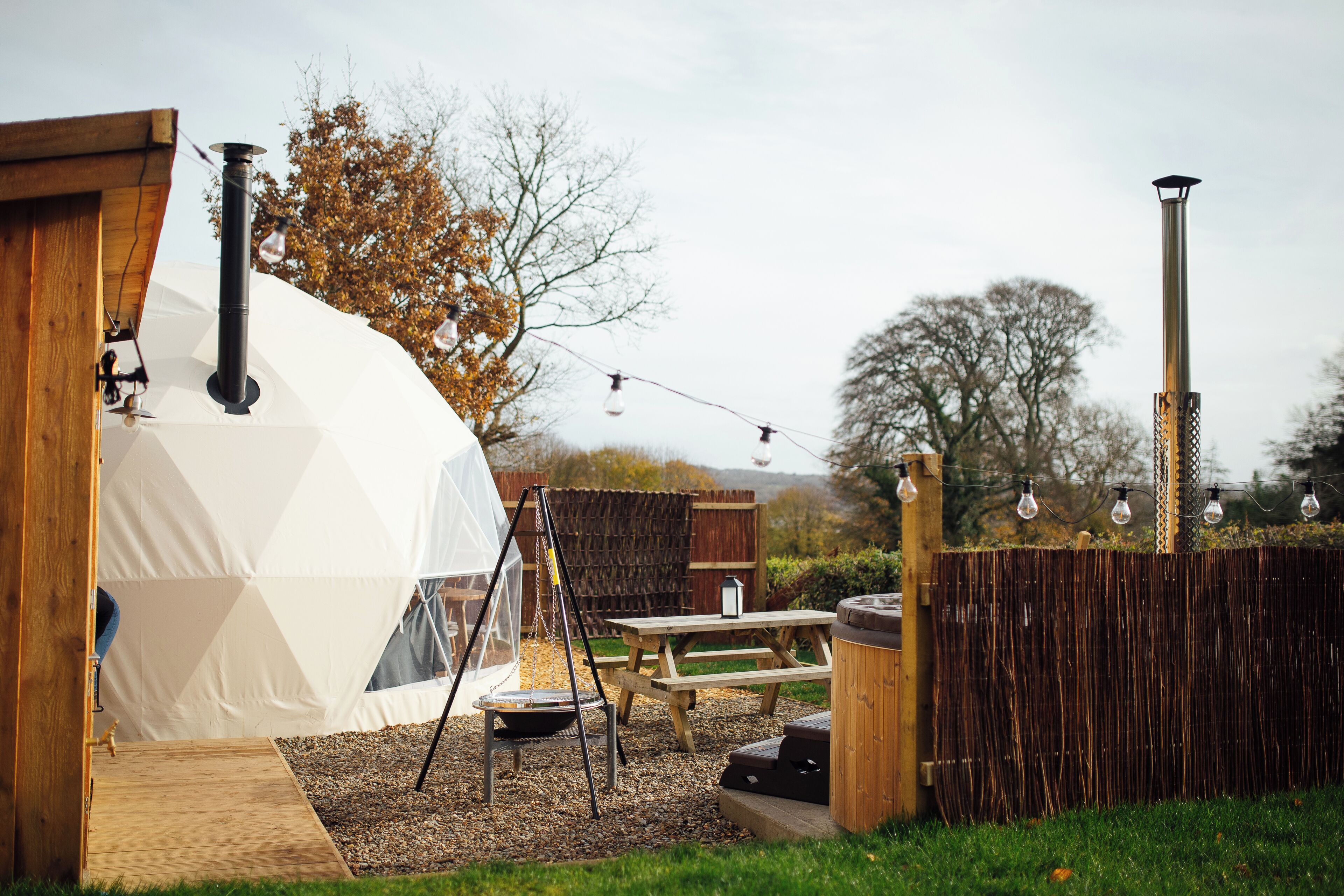 Un espace extérieur aménagé avec une tente, une terrasse en bois, une table de pique-nique et un jacuzzi.