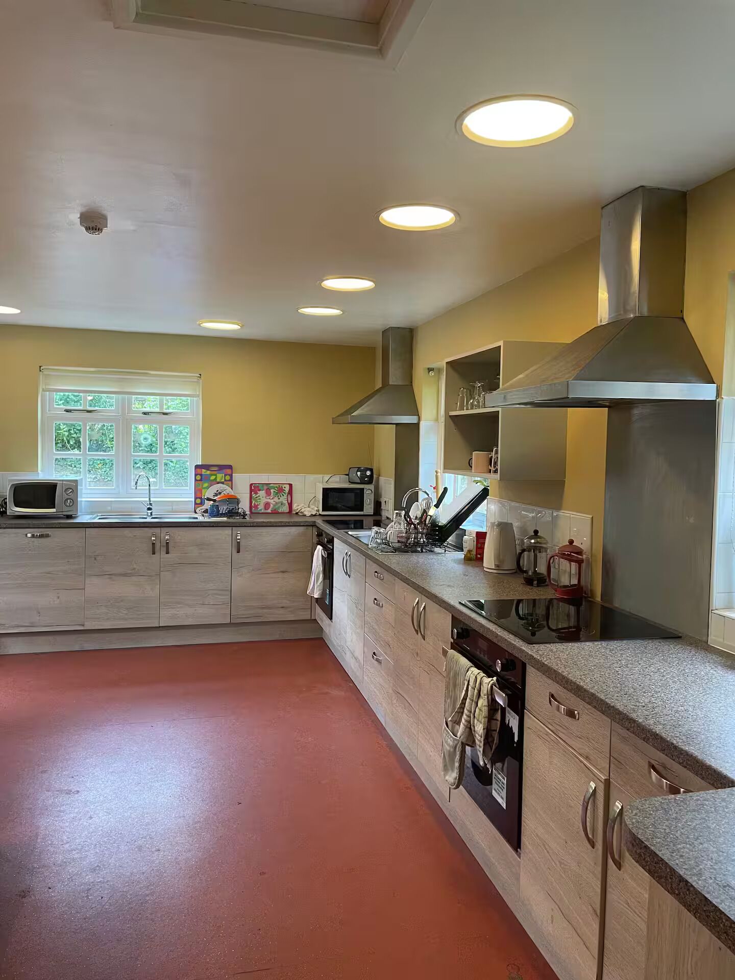 A kitchen with wooden cabinets, a microwave, a stove, and a large window with curtains.
