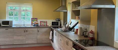 A kitchen with wooden cabinets, a microwave, a stove, and a large window with curtains.