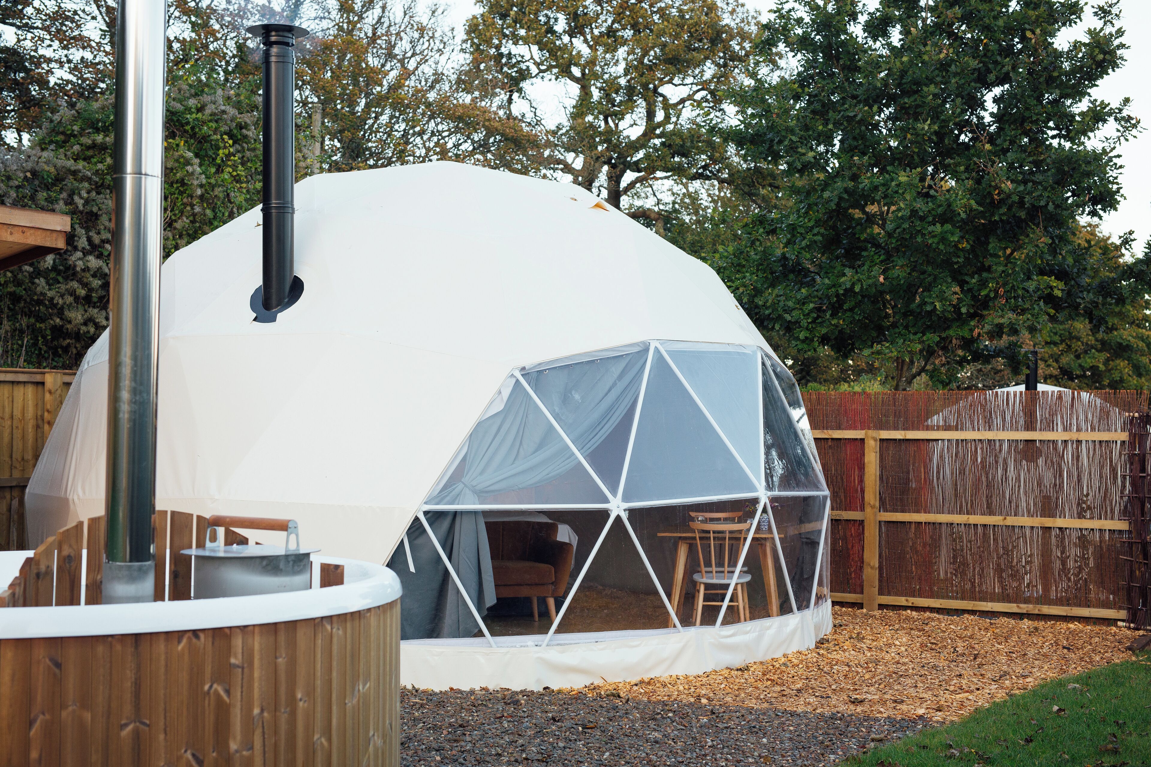 Une structure en forme de dôme géodésique dotée d’une terrasse en bois et d’un bain à remous.