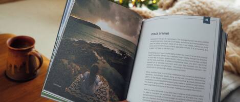 A book open to a page with a photograph of a person meditating by a beach and text about meditation benefits.
