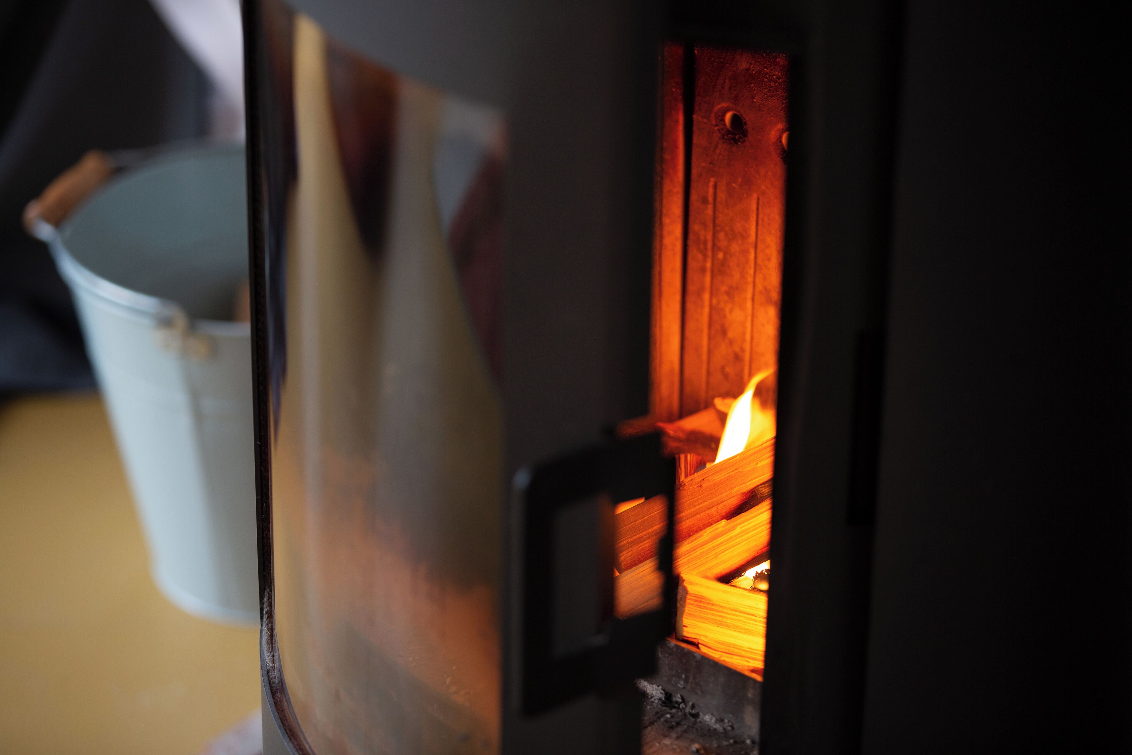 A close-up of a wood-burning stove with visible logs and a metal pot.