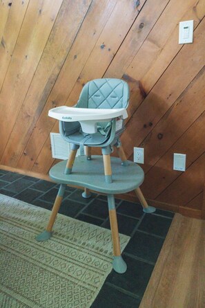A high chair with a padded seat and tray, placed on a patterned rug. - The Firefly Retreat in Lancaster county (Manheim)