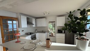 A modern kitchen with white cabinetry, a large window, and a potted plant. - Modern nest with breathtaking views (La Tronche)