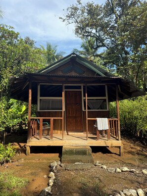 A rustic wooden house with a porch, surrounded by lush greenery. - Sabalo lodge (Sierpe)