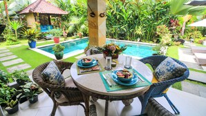 An outdoor dining area with a pool, surrounded by lush tropical plants and a small gazebo. - Brilliant 3-bedroom villa with Pool and AC in peaceful Ubud (Ubud)