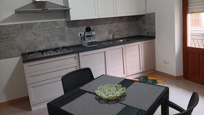 A compact kitchen with white cabinets, a gas stove, and a coffee maker. - Just minutes from Ogliastra's most beautiful beaches, rooms with en suite facilities (Cardedu)