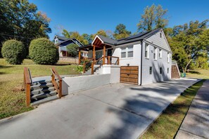 Une maison à deux étages avec un porche couvert, un escalier en bois et un garage.