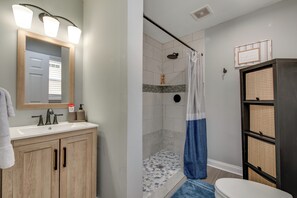 Une salle de bain avec un meuble-lavabo en bois, une douche avec un rideau bleu et des toilettes.