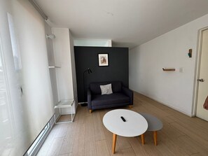 Ett modernt vardagsrum med en mörk soffa, ett vitt soffbord och ett litet runt bord.