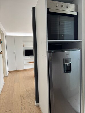 A modern kitchen with a built-in microwave, a stainless steel refrigerator, and white cabinetry. - Beautiful Apartment in the Heart of Downtown D20 (Mexico City)