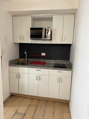A compact kitchen with white cabinets, a microwave, and a stainless steel sink. - Beautiful Apartment in the Heart of Downtown D20 (Mexico City)