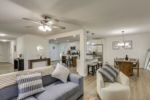 A modern living room with a grey sofa, white armchair, and a dining area with a wooden table and chairs. - 2 Mi to FSU! Group-Friendly Tallahassee Getaway (Tallahassee)