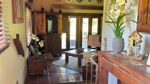 Ein gemütliches Interieur mit Fliesenboden, Holzmöbeln und Dekorationselementen, darunter ein Vogelhaus und Orchideen.