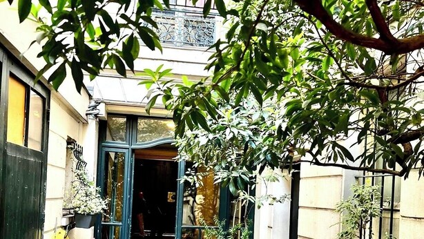 A narrow courtyard with a red table and chairs, surrounded by potted plants and a tree. - Hana House - Zen journey in the heart of Paris (Paris)