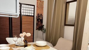 A dining area with a round table, white chairs, and a wall-mounted mirror. - Hana House - Zen journey in the heart of Paris (Paris)