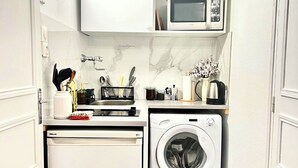 A compact kitchen with a refrigerator, microwave, and washing machine. - Hana House - Zen journey in the heart of Paris (Paris)