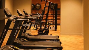 Een sportschool met loopbanden, spinningfietsen en een vastgemaakt fitnessapparaat.