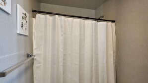 A bathroom with a shower curtain, a toilet, and a towel rack. - Modern Stay Near Fort Sill + Park & Shopping (Lawton)