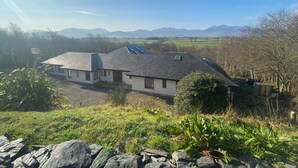 Una casa con techo inclinado, paneles solares y vistas a montañas distantes.