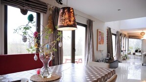 Comedor con una mesa preparada para dos, un jarrón con flores y una lámpara que ilumina el paisaje urbano.
