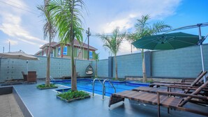 A rooftop pool area with lounge chairs, a small pool, and a view of a residential building in the background. - Amazing Pool View Apartment  perfect in Garuga-Entebbe with fitness room & WI-FI (Nkumba)