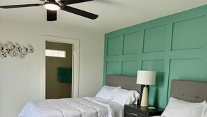 A bedroom with two beds, a ceiling fan, a green headboard, and a nightstand with a lamp. - Waterfront 3-bedroom private dock for boat access in Corpus Christi (Corpus Christi)