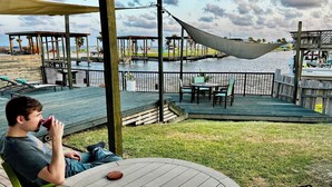 A wooden deck with a table and chairs, overlooking a body of water. - Waterfront 3-bedroom private dock for boat access in Corpus Christi (Corpus Christi)