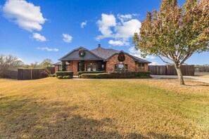 A brick house with a gabled roof, a front porch, and a Christmas wreath on the front door.