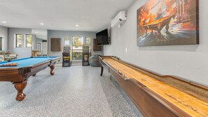 Une table de billard, une table de jeu de palet et un grand tableau abstrait accroché au mur.