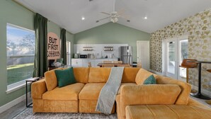 A living room with a large sectional sofa, a dining area, and a kitchen in the background. - Sunny Auburndale Retreat w/ Pool (Auburndale)