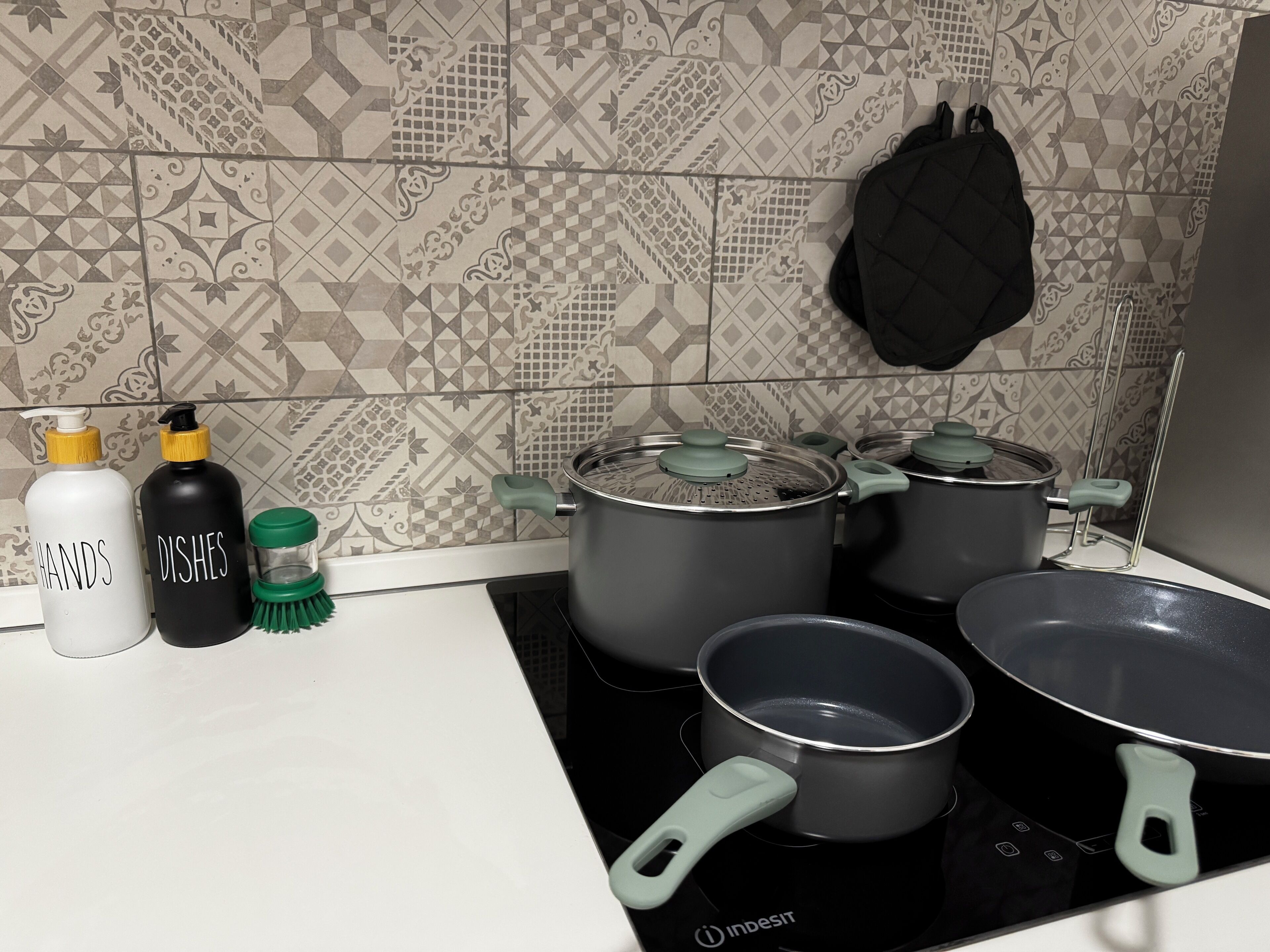 Una cocina con estufa, ollas y botellas que dicen 'MANOS' y 'PLATOS'.