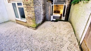 Un angolo di un edificio con un vialetto sterrato, una porta che dà su un ambiente e una finestra con vista.