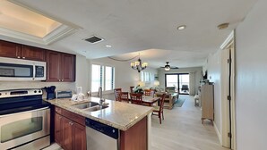 A modern kitchen with granite countertops, stainless steel appliances, and wooden cabinets. - Carlos Pointe 611 (Fort Myers Beach)