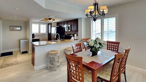 A modern kitchen with dark cabinets, stainless steel appliances, and a central island. - Carlos Pointe 611 (Fort Myers Beach)