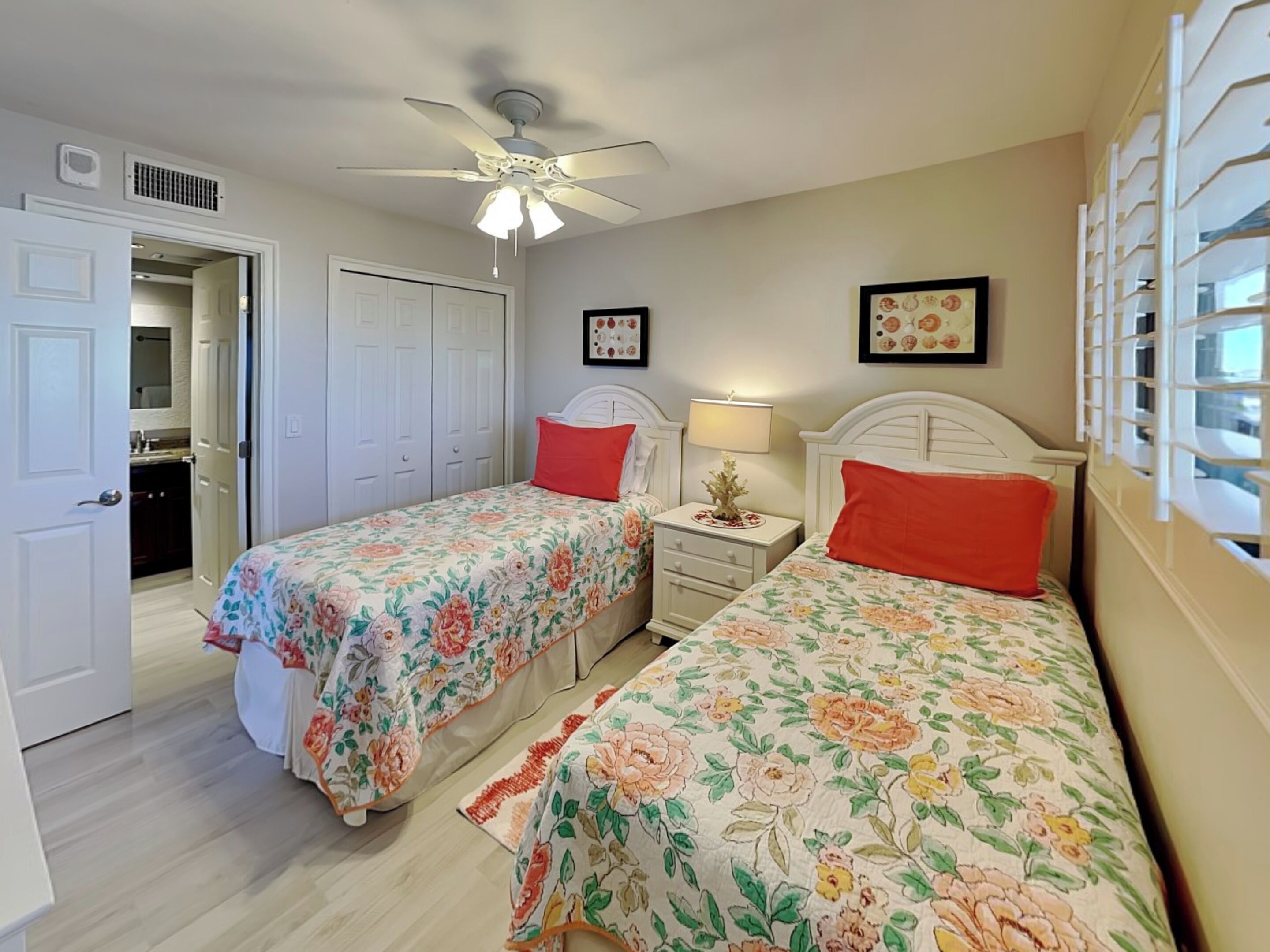A bedroom with two single beds, a ceiling fan, and a nightstand with a lamp.