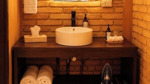 Un baño con un lavabo redondo, un espejo con luces, un perchero para toallas y un estante con toallas.