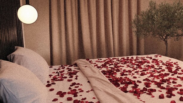 A double bed with rose petals, a bedside lamp, and a tree in the corner. - Private Romantic Retreat for Two • Luxury Escape (Chicago)