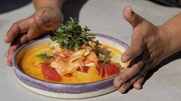 Uma tigela de sopa com um enfeite por cima, segurada por duas mãos.