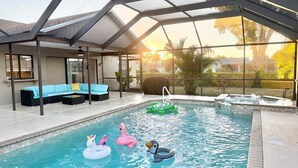 Una piscina interna con struttura in vetro, un'area relax con divano e giochi gonfiabili.