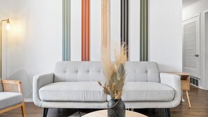 Een moderne woonkamer met een grijze bank, een klein bijzettafeltje en een vloerlamp.