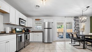 Een moderne keuken met witte kasten, roestvrijstalen apparatuur en een eetgedeelte met een tafel en stoelen.