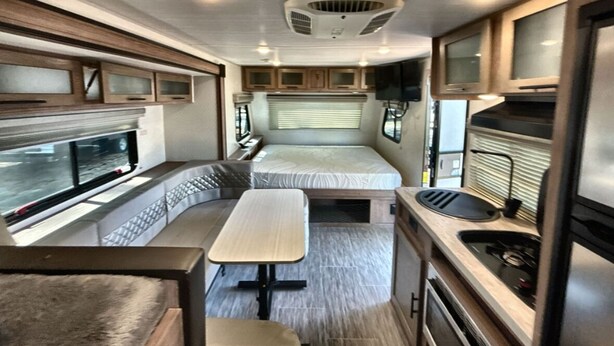 Interior compacto de una autocaravana con kitchenette, comedor y litera.
