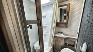 Un baño pequeño con inodoro, lavamanos y ducha.