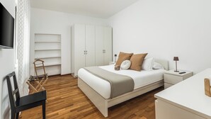 Une chambre à coucher moderne, équipée d’un lit, de tables de chevet, d’un téléviseur et d’une armoire.
