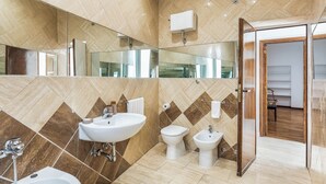 Une salle de bain moderne avec un grand miroir, un lavabo, des toilettes et un bidet.