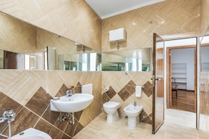 A modern bathroom with a large mirror, a sink, a toilet, and a bidet. - Atrhome- Penthouse Tritone (Rome)