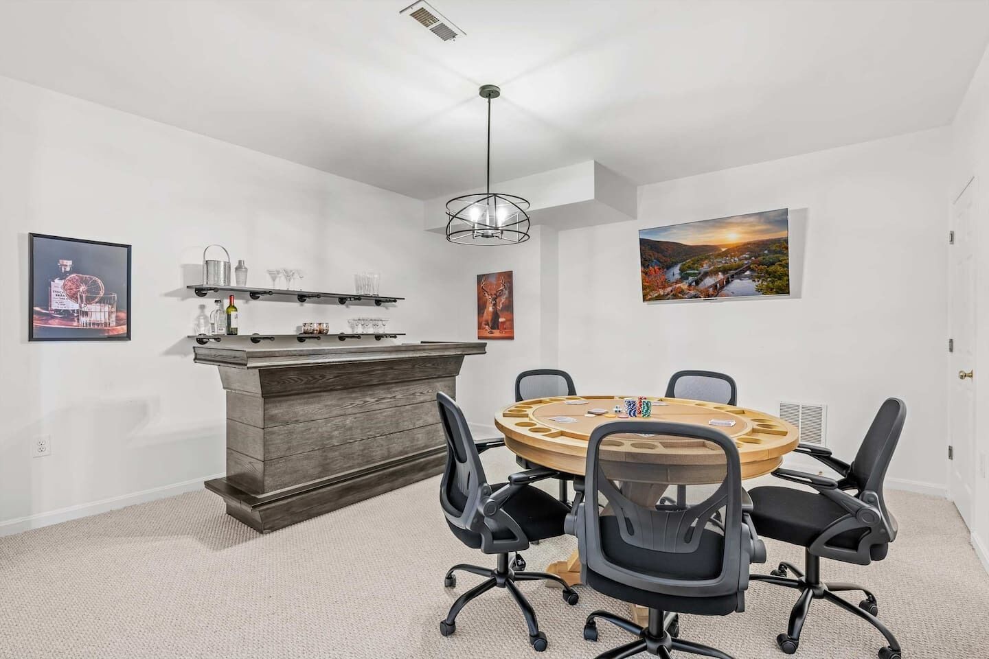 A conference room with a round table, four chairs, a wooden bar, and artwork on the walls.
