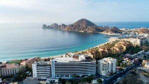 A coastal cityscape with a prominent mountain, beachfront hotels, and a marina. - Corazon Cabo Infinity King Sunset View, Spend New Year's in Cabo. (Cabo San Lucas)